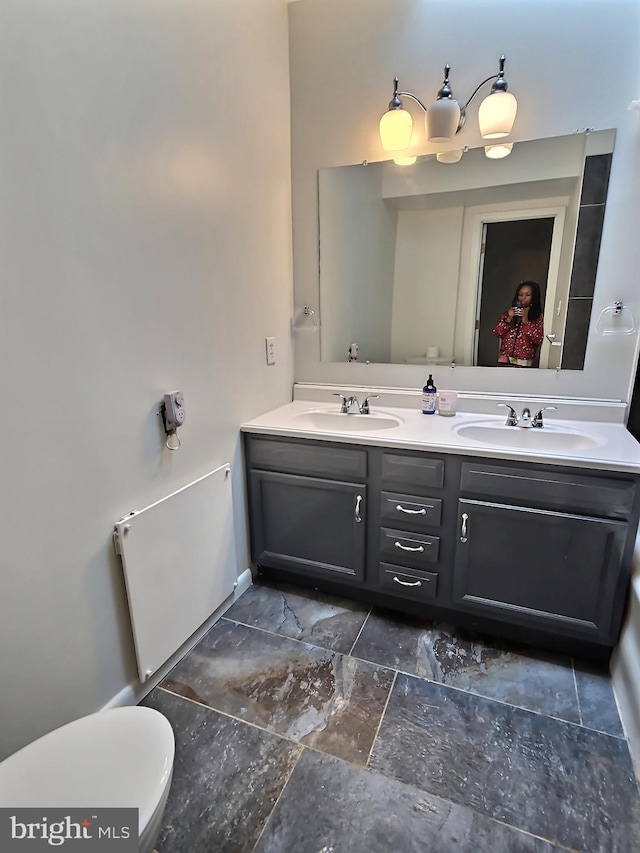 full bathroom with double vanity, toilet, and stone finish flooring