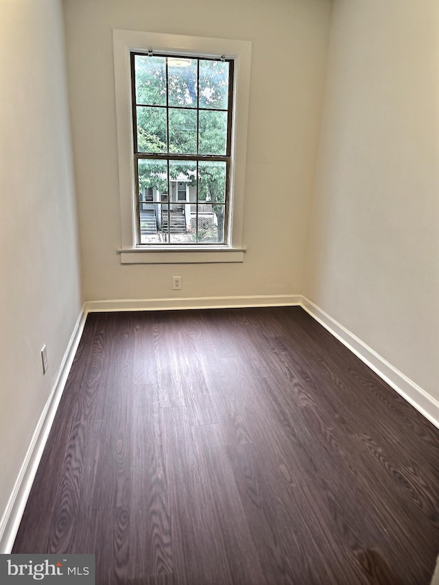 spare room featuring dark wood-style flooring and baseboards