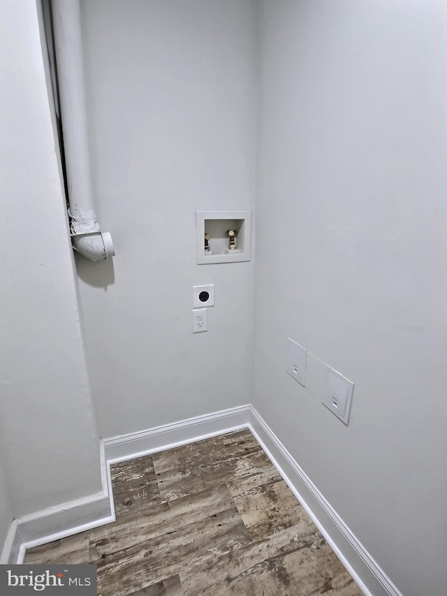 clothes washing area with hookup for an electric dryer, washer hookup, wood finished floors, and baseboards