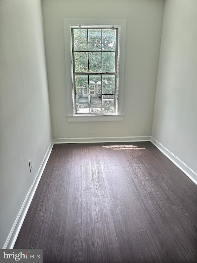 spare room featuring dark wood-type flooring and baseboards