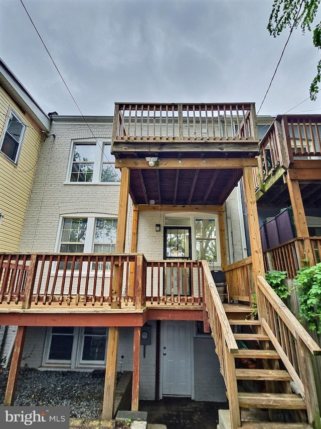 rear view of property featuring brick siding and stairway