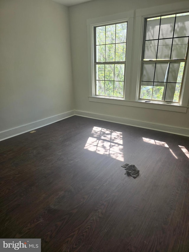 empty room featuring baseboards and dark wood-style floors