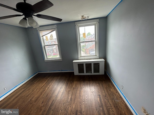 unfurnished room with wood finished floors, a ceiling fan, and baseboards