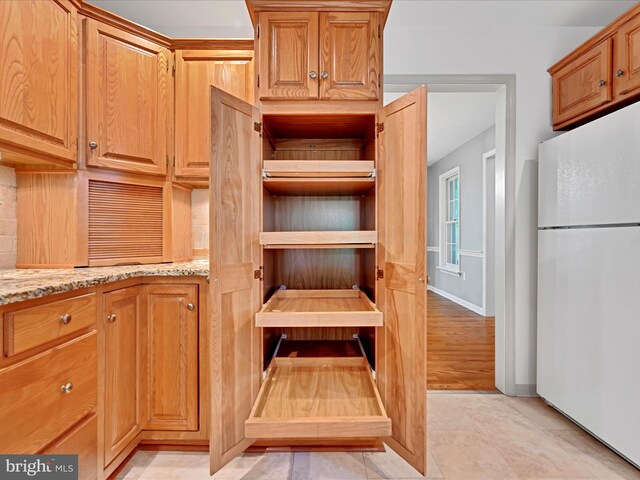 320 N Ridge Rd, Reinholds, PA 17569 - kitchen view of freestanding refrigerator, light stone counters, baseboards, and decorative backsplash