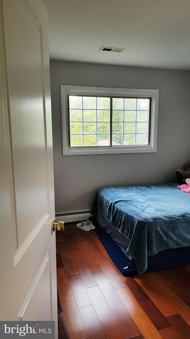 15030 Alabama Ave, Woodbridge, VA 22191 - bedroom featuring a baseboard heating unit, multiple windows, and wood finished floors