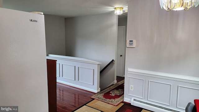 15030 Alabama Ave, Woodbridge, VA 22191 - hall featuring baseboard heating, an upstairs landing, a chandelier, dark wood finished floors, and baseboards