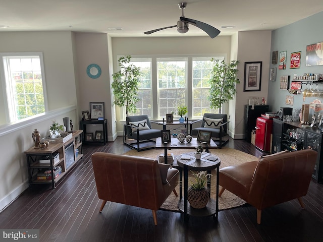 living area featuring a ceiling fan, wood-type flooring, baseboards, and a dry bar
