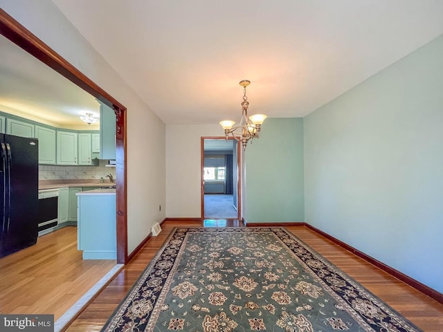 12419 Balston Rd, Philadelphia, PA 19154 - unfurnished dining area featuring a chandelier, light wood-type flooring, baseboards, and a sink