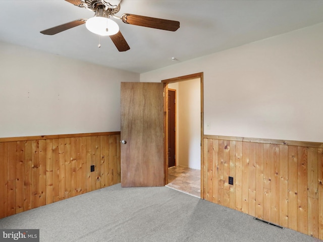 12417 Mount Savage Rd, Mount Savage, MD 21545 - spare room featuring a wainscoted wall, carpet flooring, wood walls, and a ceiling fan