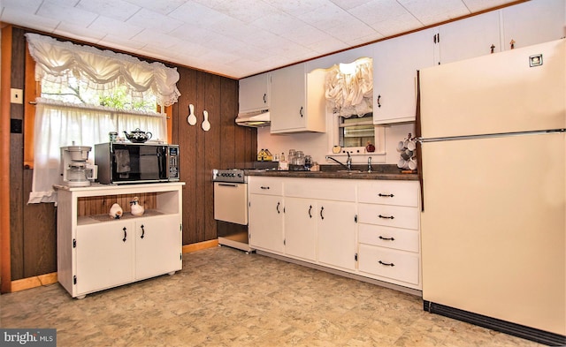 136 Camp Meeting Cir, Herndon, PA 17830 - kitchen with freestanding refrigerator, black microwave, gas stove, wooden walls, and dark countertops