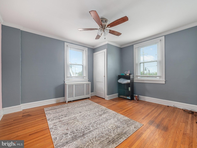 bedroom featuring radiator, hardwood / wood-style flooring, ornamental molding, baseboards, and a closet