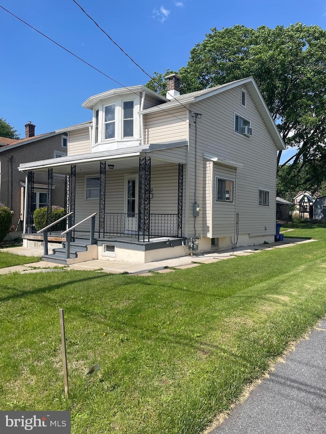 view of front of house with a chimney, a front yard, and covered porch