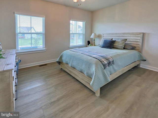bedroom featuring multiple windows, baseboards, and wood finished floors