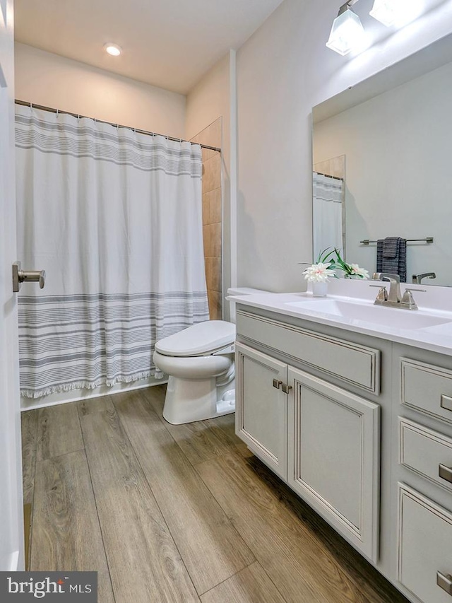 bathroom featuring vanity, toilet, wood finished floors, and a shower with curtain