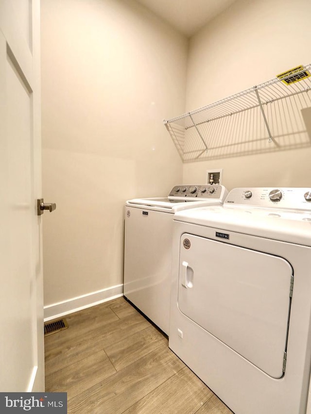 laundry area featuring washing machine and dryer, light wood-style floors, and baseboards