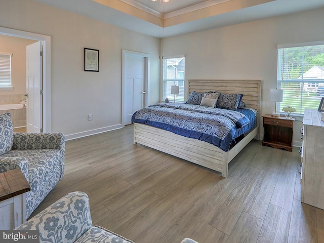 bedroom with wood finished floors, multiple windows, baseboards, and crown molding