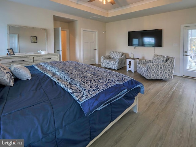 bedroom with wood finished floors, ornamental molding, ceiling fan, baseboards, and a tray ceiling