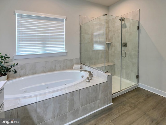 full bathroom with a shower stall, wood finished floors, a jetted tub, and baseboards