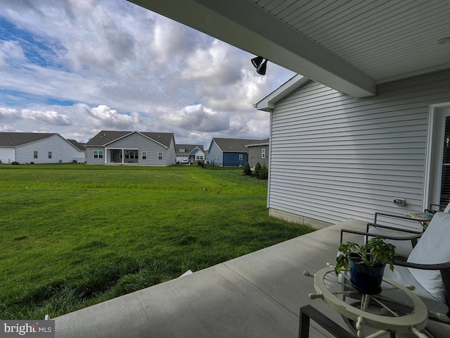 view of grassy yard with a residential view and a patio