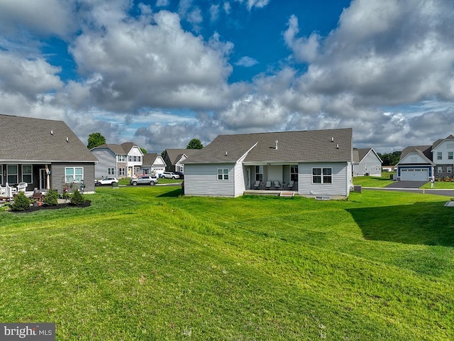 back of property with a patio area, a lawn, and a residential view
