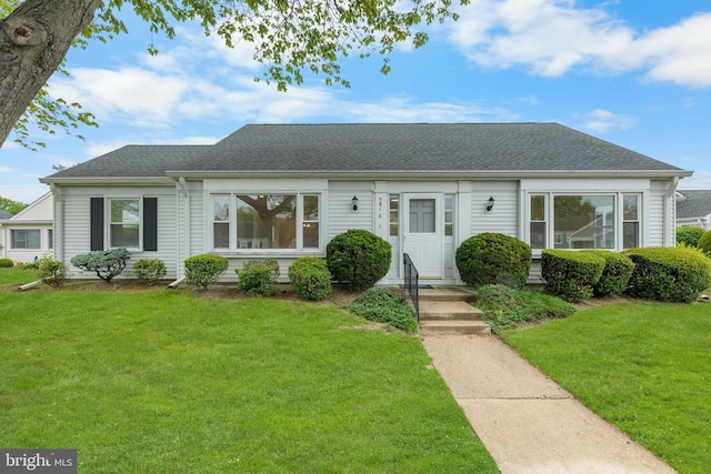 view of front of home featuring a front yard and a shingled roof