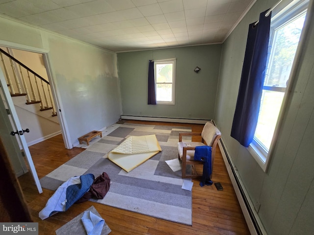 26689 Mariners Rd, Crisfield, MD 21817 - unfurnished room featuring a baseboard heating unit, plenty of natural light, wood finished floors, ornamental molding, and stairs