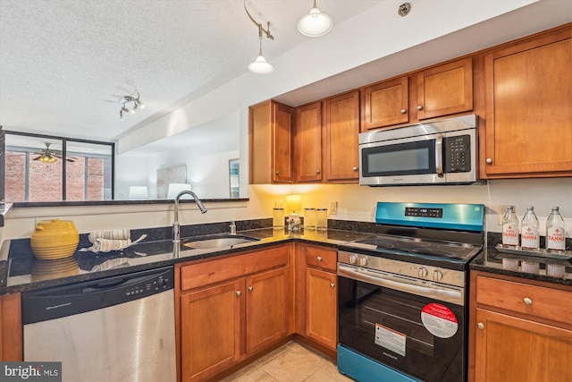 1001 N Vermont St Unit 812, Arlington, VA 22201 - kitchen with stainless steel appliances, brown cabinets, a textured ceiling, dark stone counters, and a sink