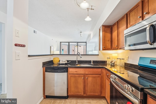 1001 N Vermont St Unit 812, Arlington, VA 22201 - kitchen featuring appliances with stainless steel finishes, rail lighting, brown cabinetry, a sink, and dark stone countertops