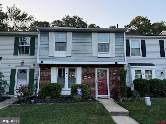 view of property with a front yard and brick siding