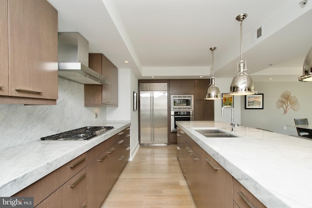 2818 Connecticut Ave NW Unit 503, Washington, DC 20008 - kitchen featuring built in appliances, wall chimney exhaust hood, a sink, light wood finished floors, and decorative light fixtures