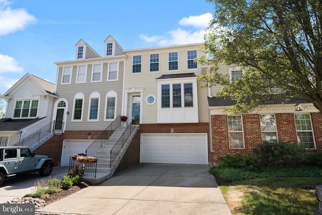 view of property featuring an attached garage, driveway, brick siding, and stairs