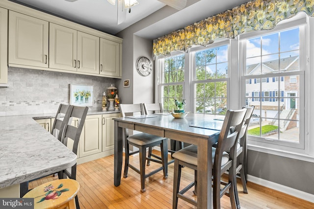 dining room featuring light wood-type flooring, a ceiling fan, and baseboards