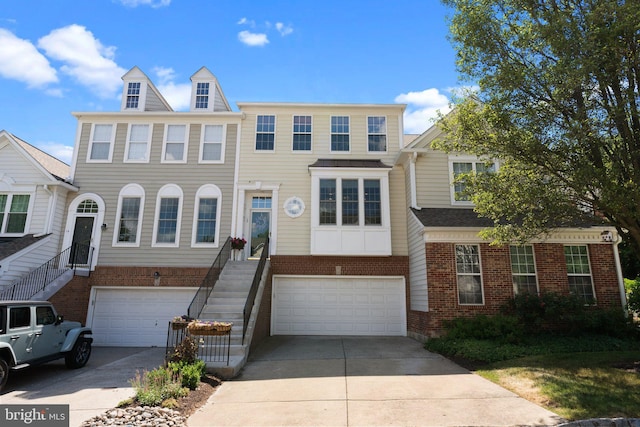 townhome / multi-family property with brick siding, a garage, and driveway