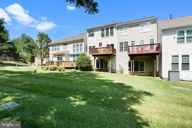rear view of house with central AC, a deck, and a lawn