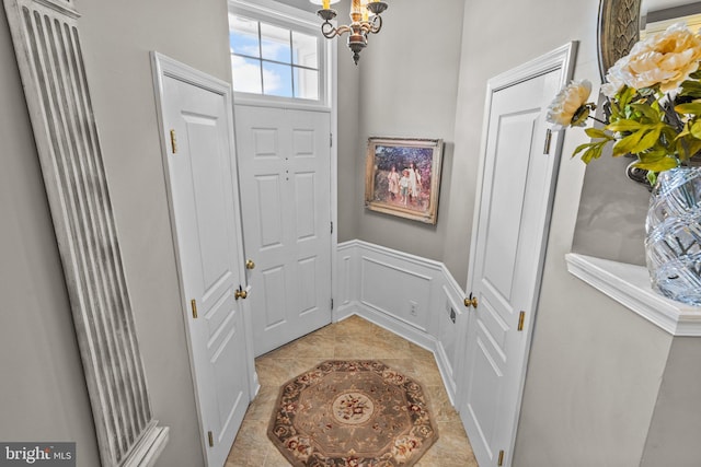 entryway featuring a chandelier, a wainscoted wall, and a decorative wall
