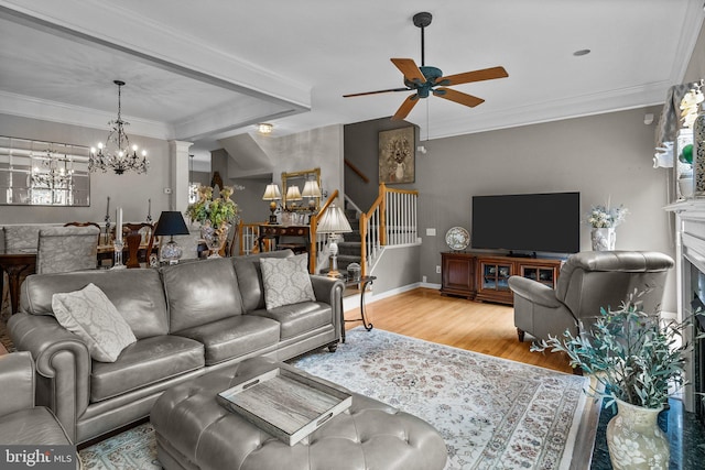 living area with a chandelier, ceiling fan, stairs, wood finished floors, and ornamental molding