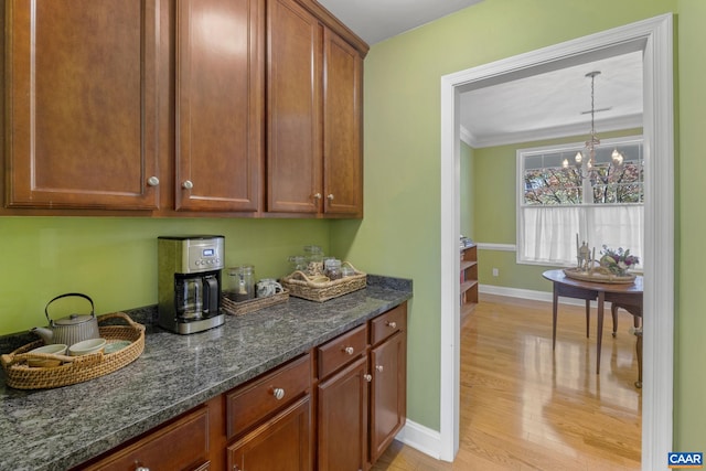 3080 Morewood Ln, Charlottesville, VA 22901 - kitchen with light wood finished floors, baseboards, dark stone counters, ornamental molding, and a chandelier