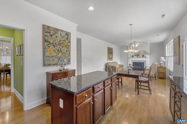 3080 Morewood Ln, Charlottesville, VA 22901 - kitchen featuring a glass covered fireplace, light wood finished floors, ceiling fan, a kitchen island, and dark stone counters