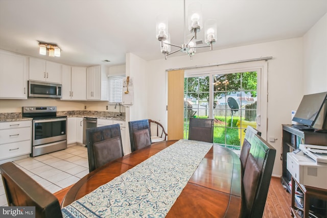 1650 Woodtree Ct E, Annapolis, MD 21409 - kitchen with stainless steel appliances, a chandelier, a sink, white cabinetry, and light tile patterned floors