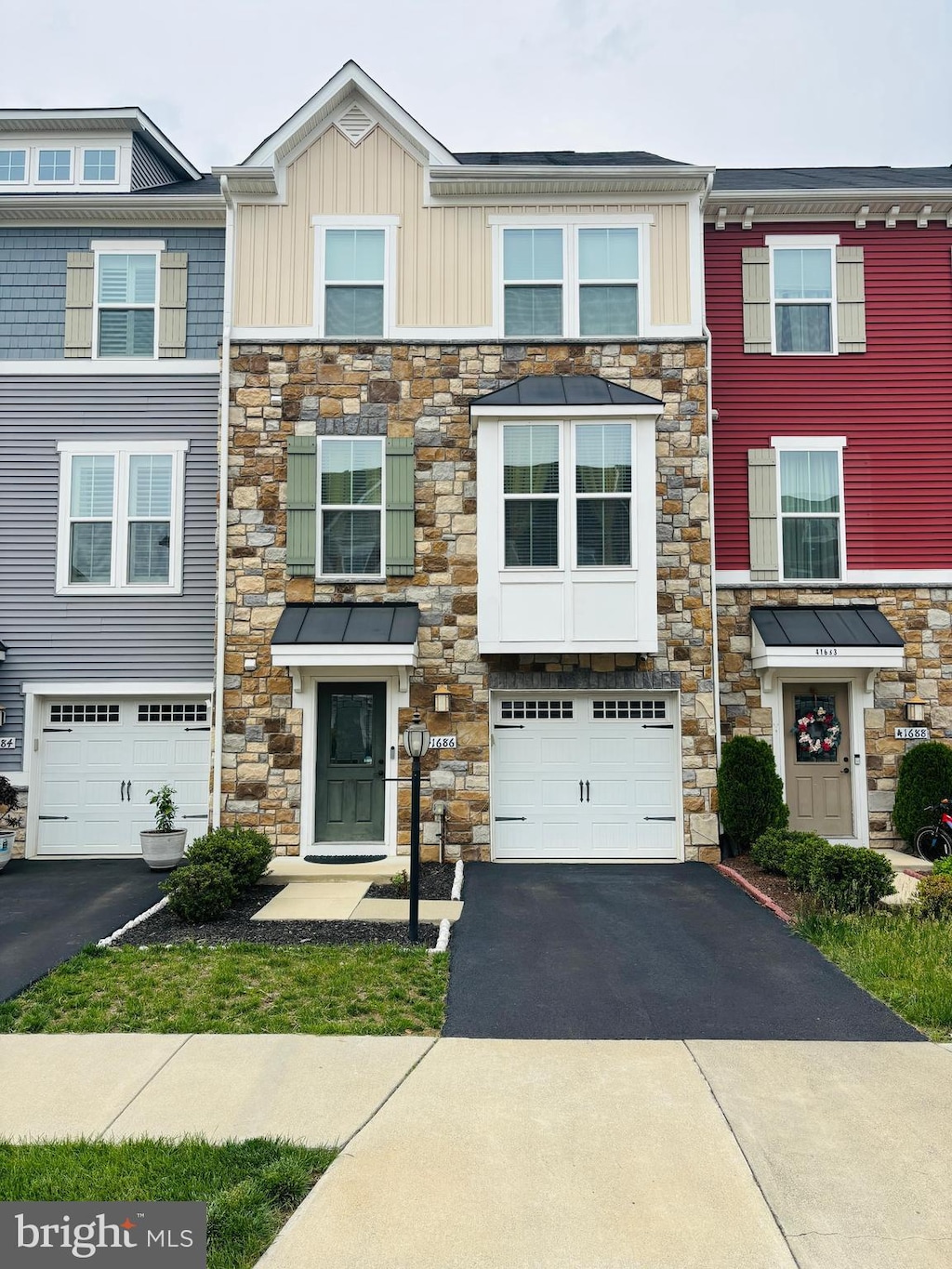 view of property featuring stone siding, driveway, and a garage