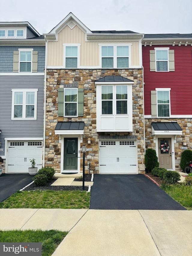 view of property featuring stone siding, driveway, and a garage