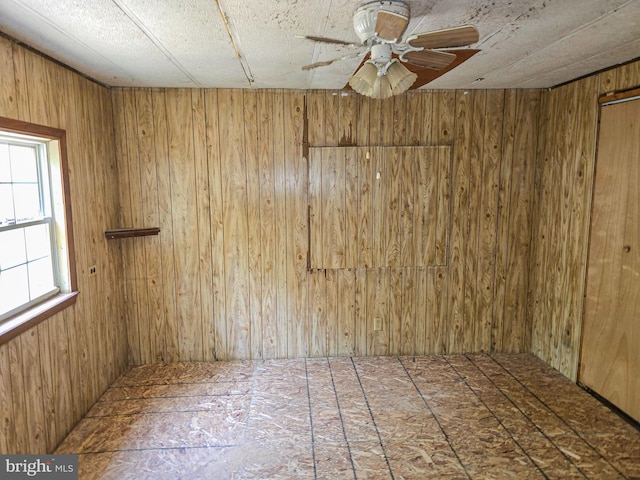 spare room featuring a ceiling fan and wood walls