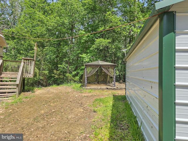 view of yard featuring a gazebo, a deck, and stairs