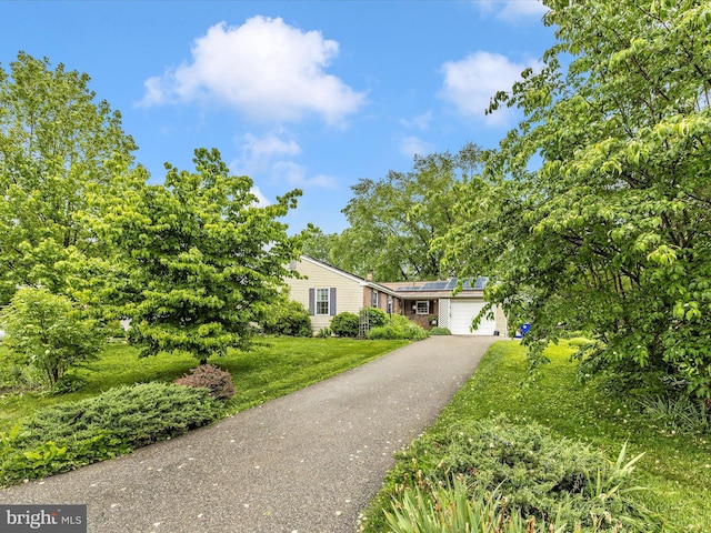 4310 Zircon Rd, Middletown, MD 21769 - view of front of property featuring a garage, a front lawn, roof mounted solar panels, and driveway
