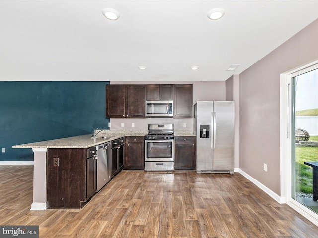 11044 Cross Fields Dr, Waynesboro, PA 17268 - kitchen featuring stainless steel appliances, dark brown cabinets, wood finished floors, a peninsula, and light stone countertops