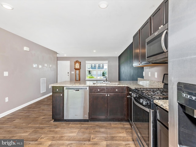 11044 Cross Fields Dr, Waynesboro, PA 17268 - kitchen featuring appliances with stainless steel finishes, a peninsula, dark brown cabinets, light wood-type flooring, and recessed lighting
