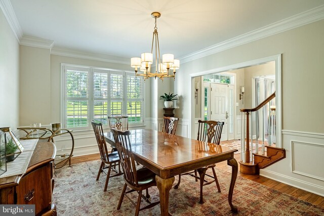 201 Ivystone Dr, Downingtown, PA 19335 - dining space featuring ornamental molding, a chandelier, wood finished floors, a wainscoted wall, and a decorative wall