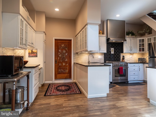 5607 Meridian Rd, Gibsonia, PA 15044 - kitchen featuring high end stove, wall chimney range hood, freestanding refrigerator, white cabinets, and dark countertops