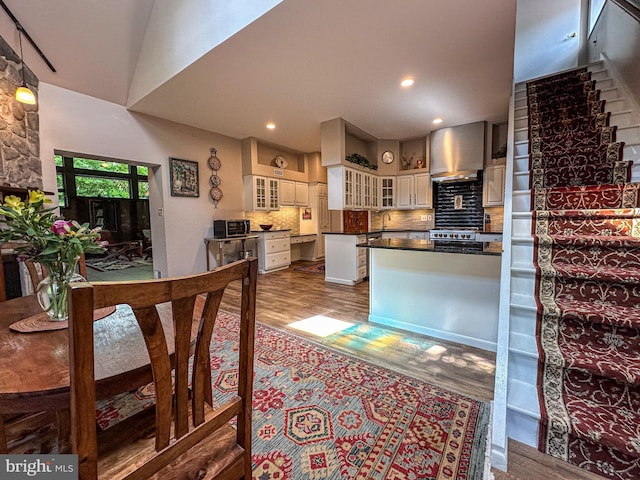 5607 Meridian Rd, Gibsonia, PA 15044 - kitchen featuring wood finished floors, dark countertops, decorative backsplash, glass insert cabinets, and white cabinetry