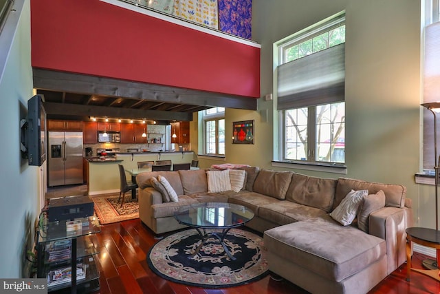 living room with dark wood-type flooring and a towering ceiling
